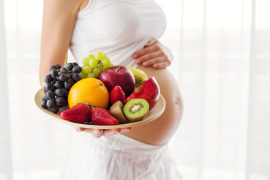 kobieta w ciąży z talerzem owoców