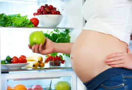 kobieta w ciąży wybierająca owoce z lodówki