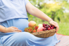 kobieta w ciąży z koszem owoców