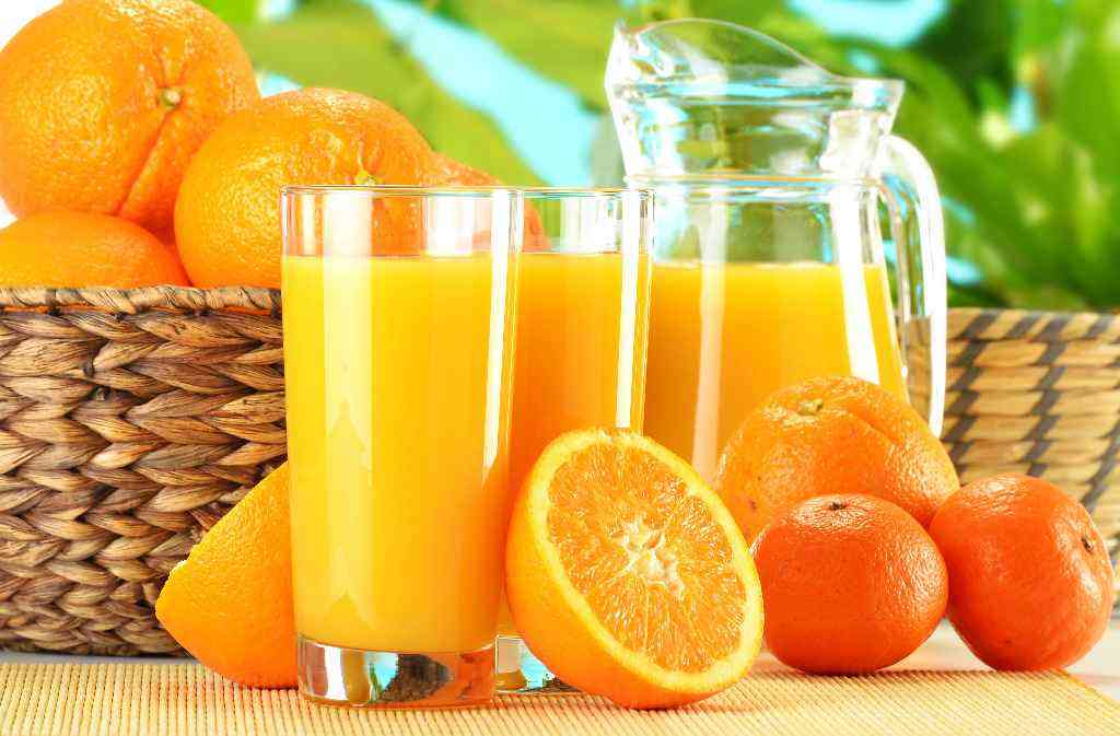 pomarańcze w koszu i sok z pomarańczy