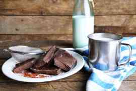 kawałki czekolady na talerzu i mleko w butelce