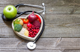 warzywa i owoce w miseczce w kształcie serca i słuchawki medyczne
