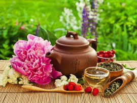 herbata owocowa w dzbanku na stole kwiaty i owoce na tle ogrodu